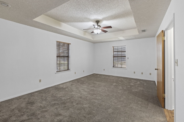 carpeted spare room with a tray ceiling, a textured ceiling, visible vents, and a ceiling fan