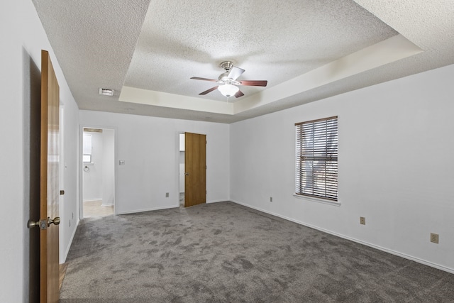 unfurnished room with a tray ceiling, baseboards, visible vents, ceiling fan, and carpet