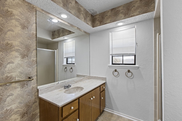 bathroom with a shower stall, vanity, and a textured ceiling