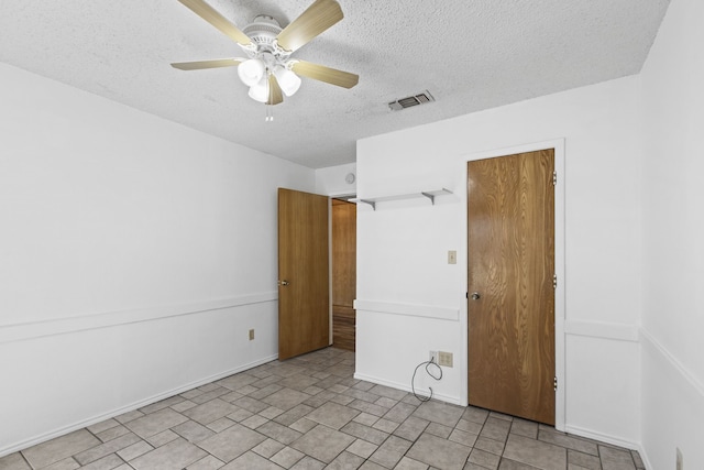 spare room with a textured ceiling, visible vents, baseboards, and a ceiling fan