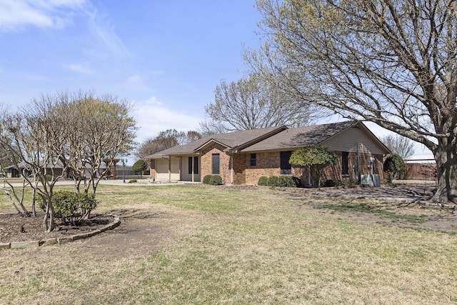 ranch-style house with brick siding, a shingled roof, fence, and a front lawn