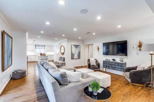living area featuring recessed lighting, light wood-type flooring, crown molding, and baseboards