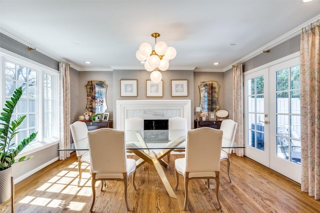 dining area featuring light wood-style floors, a wealth of natural light, crown molding, and an inviting chandelier