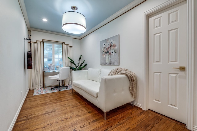 living area with baseboards, crown molding, and wood finished floors