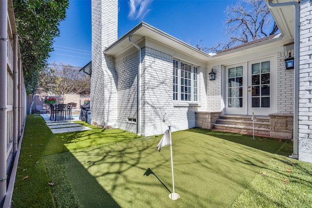 exterior space featuring a chimney, french doors, fence, entry steps, and brick siding