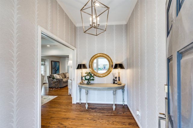 entryway featuring wallpapered walls, wood finished floors, ornamental molding, and a notable chandelier