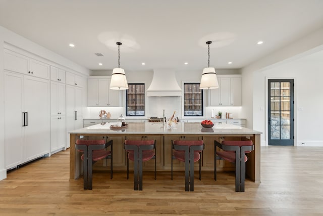 9518 Still Creek Ln, Dallas, TX 75238 - kitchen with custom range hood, light wood finished floors, white cabinets, a breakfast bar area, and recessed lighting