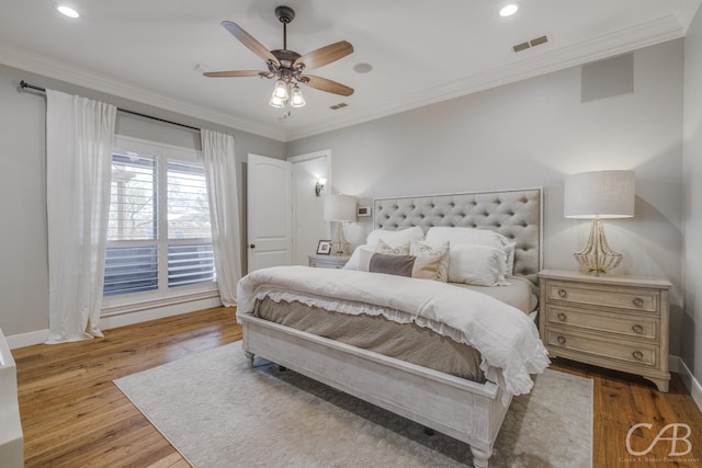 bedroom featuring visible vents, baseboards, ornamental molding, and wood finished floors