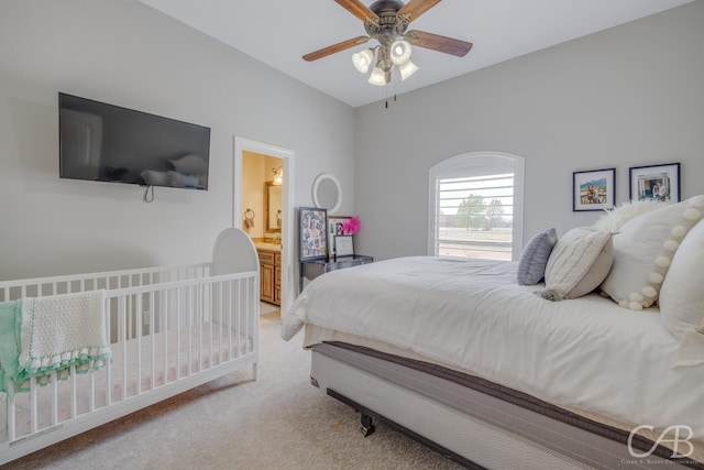 bedroom featuring ensuite bathroom, a ceiling fan, and light carpet