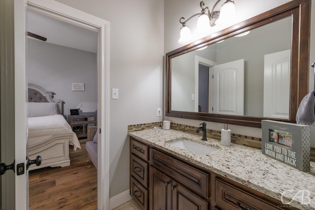 bathroom featuring baseboards, connected bathroom, vanity, and wood finished floors