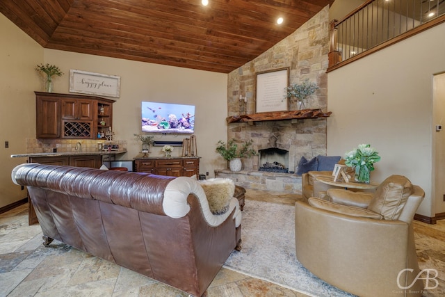 living room featuring high vaulted ceiling, a stone fireplace, stone tile floors, wood ceiling, and baseboards