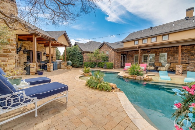 outdoor pool featuring a fireplace and a patio area
