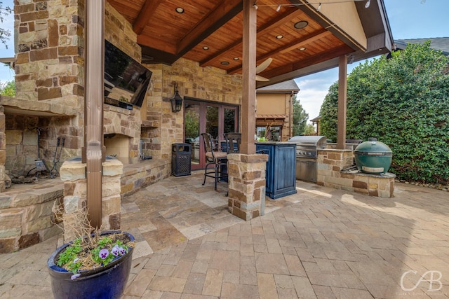 view of patio / terrace featuring grilling area, an outdoor stone fireplace, and an outdoor kitchen