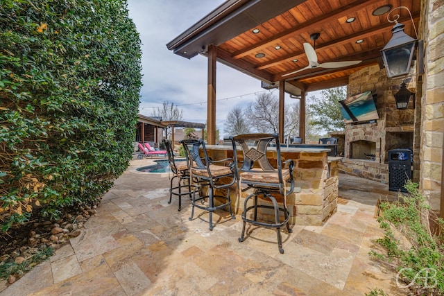 view of patio with an outdoor stone fireplace and outdoor dry bar