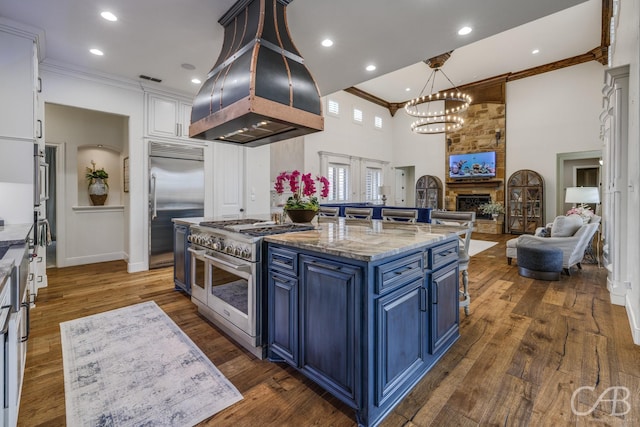 kitchen featuring a notable chandelier, ornamental molding, a high ceiling, blue cabinetry, and high end appliances