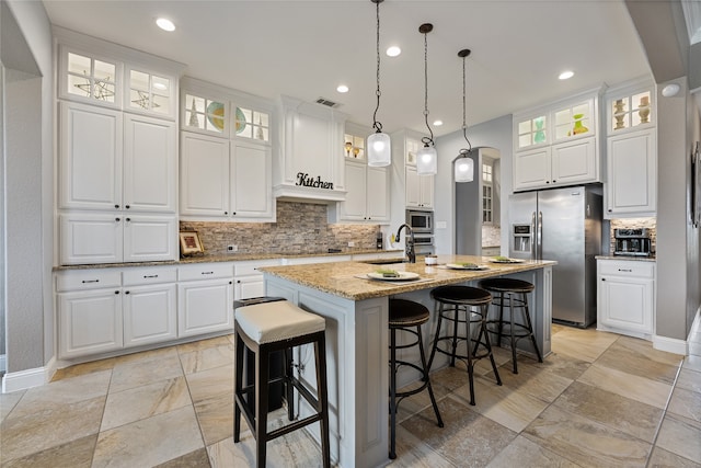 kitchen featuring decorative backsplash, visible vents, appliances with stainless steel finishes, arched walkways, and baseboards