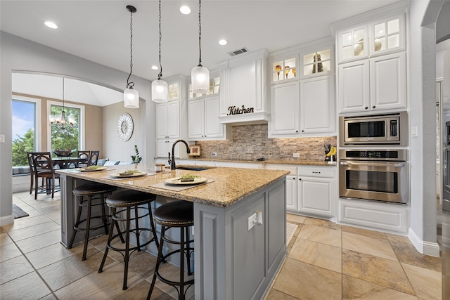 kitchen with visible vents, arched walkways, decorative backsplash, and stainless steel appliances