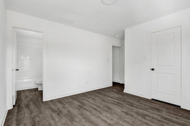 2616 S Fannin Ave, Denison, TX 75020 - unfurnished bedroom with dark wood-type flooring, ensuite bathroom, and baseboards