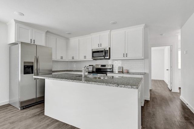 2616 S Fannin Ave, Denison, TX 75020 - kitchen with wood finished floors, stainless steel appliances, tasteful backsplash, white cabinetry, and light stone counters