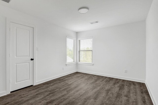 2616 S Fannin Ave, Denison, TX 75020 - spare room featuring baseboards, visible vents, and dark wood-type flooring