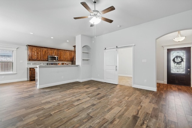 3911 Bridle Path Ln, Sanger, TX 76266 - unfurnished living room with a barn door, wood finished floors, ceiling fan, arched walkways, and recessed lighting