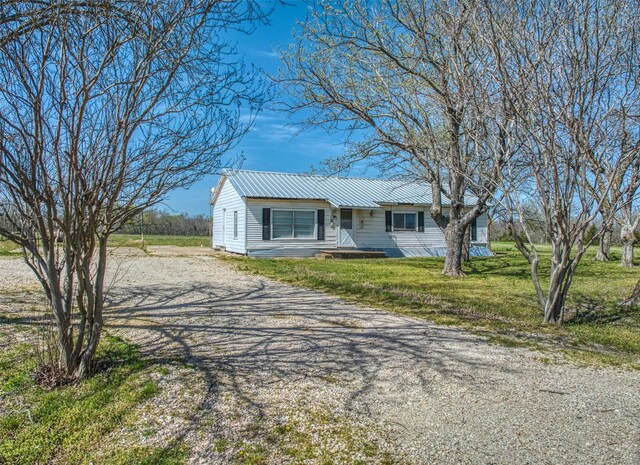 view of front of house featuring metal roof and a front lawn