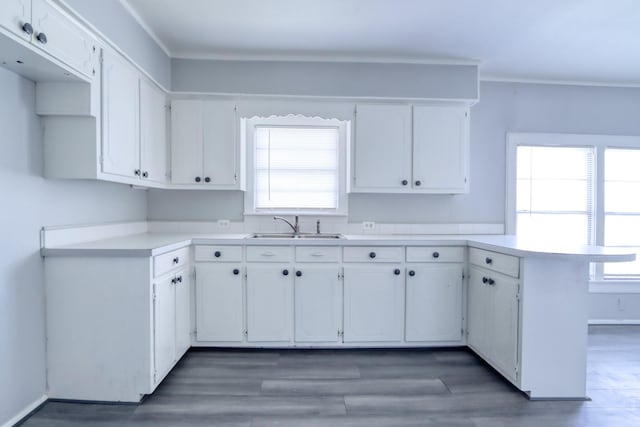 kitchen featuring white cabinets, a sink, light countertops, and a peninsula