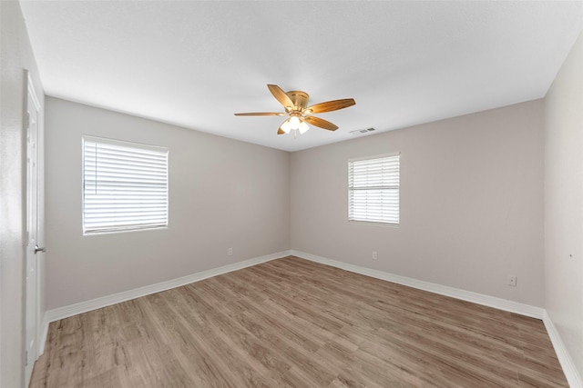 unfurnished room featuring baseboards, ceiling fan, visible vents, and light wood-style floors