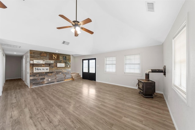 unfurnished living room featuring visible vents, a wood stove, and a ceiling fan