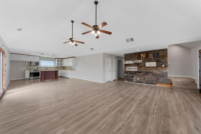 unfurnished living room with light wood finished floors, visible vents, and high vaulted ceiling