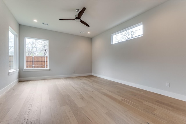 empty room with light wood finished floors, visible vents, and a healthy amount of sunlight