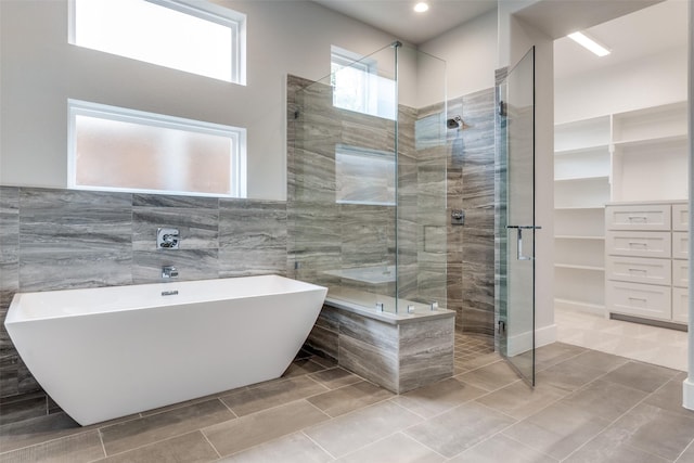 full bath with a soaking tub, a stall shower, and tile walls