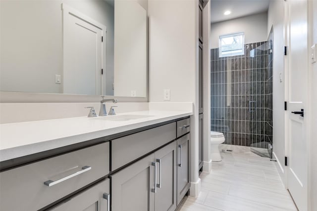 full bathroom featuring tile patterned floors, a tile shower, toilet, and vanity