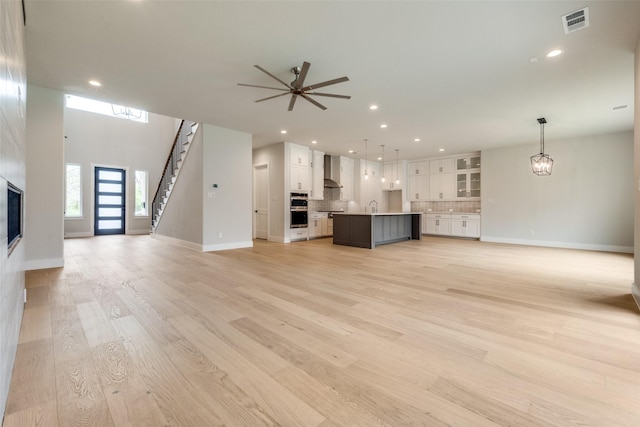 unfurnished living room with visible vents, recessed lighting, light wood-style floors, and a large fireplace