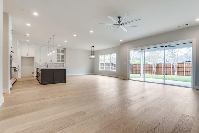 unfurnished living room featuring light wood-style floors, a sink, and recessed lighting