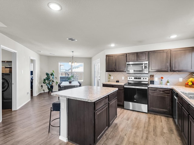 6348 Sloop St, Fort Worth, TX 76179 - kitchen featuring light countertops, an inviting chandelier, stainless steel appliances, washer / clothes dryer, and dark brown cabinetry