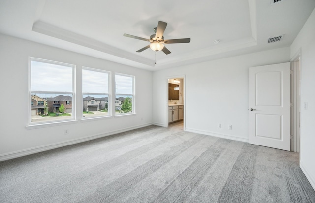 244 Kistler Dr, Little Elm, TX 76227 - unfurnished bedroom with a raised ceiling, light carpet, baseboards, and connected bathroom