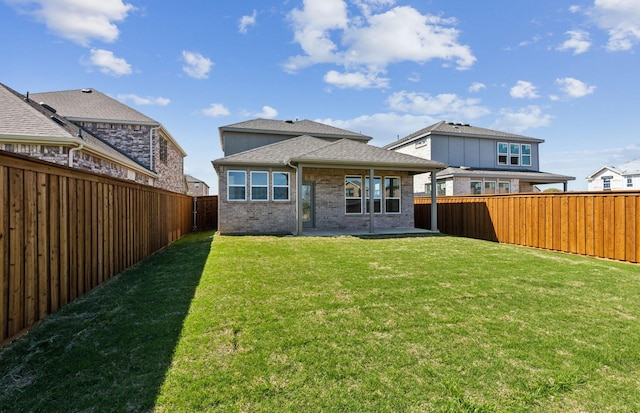 back of house featuring a patio, a yard, a fenced backyard, and brick siding
