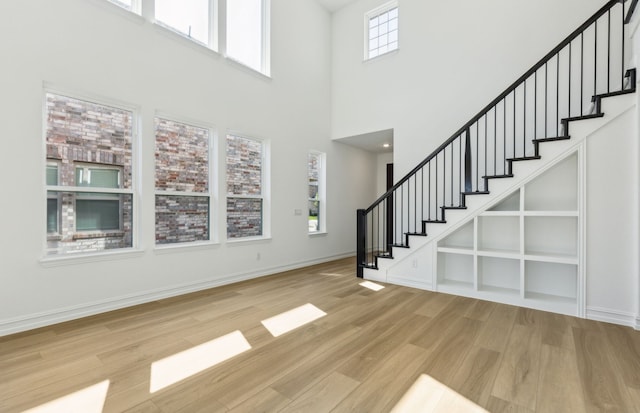 foyer with a towering ceiling, stairs, wood finished floors, and baseboards