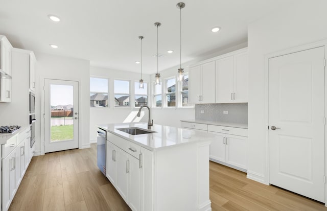 kitchen with light wood-style flooring, a sink, appliances with stainless steel finishes, and light countertops