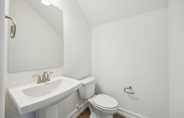244 Kistler Dr, Little Elm, TX 76227 - half bathroom with wood finished floors, toilet, baseboards, lofted ceiling, and a sink