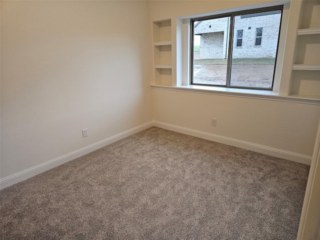 spare room with carpet floors, built in features, and baseboards