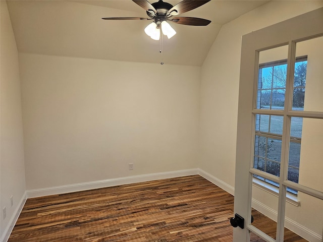 spare room featuring dark wood-style floors, lofted ceiling, ceiling fan, and baseboards