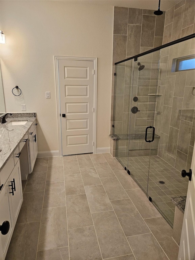full bathroom with a stall shower, baseboards, tile patterned flooring, and vanity