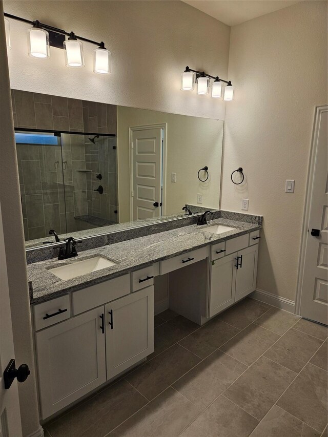 full bathroom featuring a stall shower, double vanity, a sink, and tile patterned floors