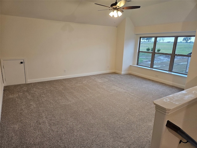 carpeted spare room with baseboards, vaulted ceiling, and a ceiling fan