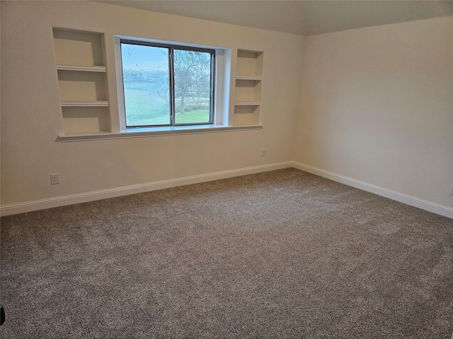 spare room featuring carpet flooring, built in features, and baseboards