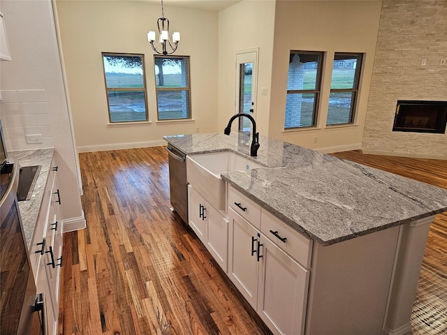 kitchen featuring dark wood-style flooring, white cabinets, open floor plan, an inviting chandelier, and stainless steel dishwasher
