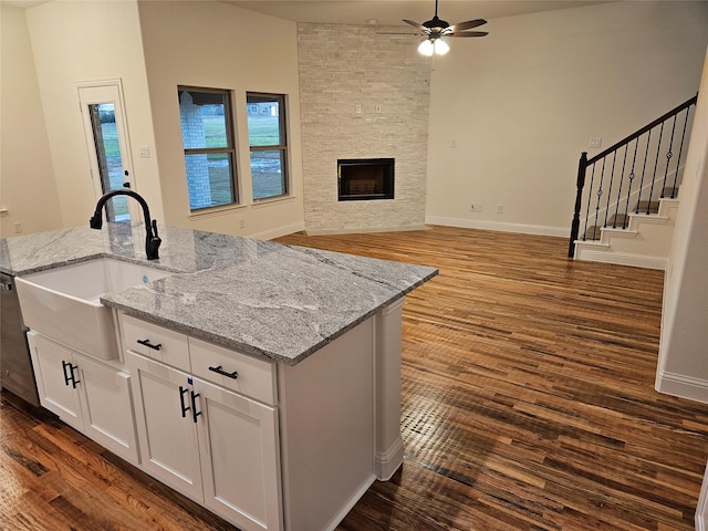 kitchen featuring dark wood-style flooring, white cabinets, a ceiling fan, a sink, and an island with sink