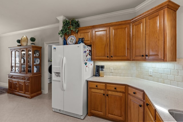 kitchen featuring backsplash, ornamental molding, brown cabinets, and white fridge with ice dispenser